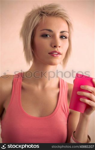 Hot blond girl with short hair holding plastic cup and looking at camera