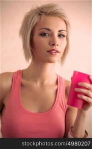 Hot blond girl with short hair holding plastic cup and looking at camera