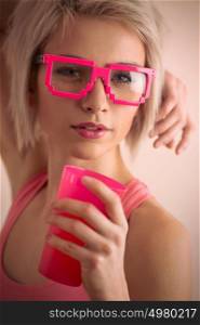 Hot blond girl with short hair wearing freak glasses holding plastic cup and looking at camera