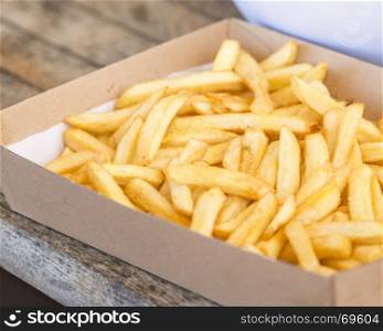 Hot bowl of french fries salted on a wooden table