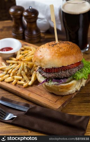 hot burger serving on wooden board with dark beer in restaurant