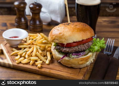 hot burger serving on wooden board with dark beer in restaurant