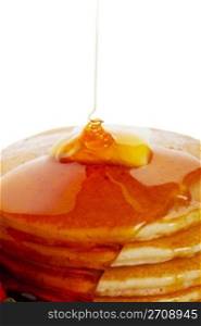 Hot buttered pancakes with maple syrup drizzling down onto the stack.