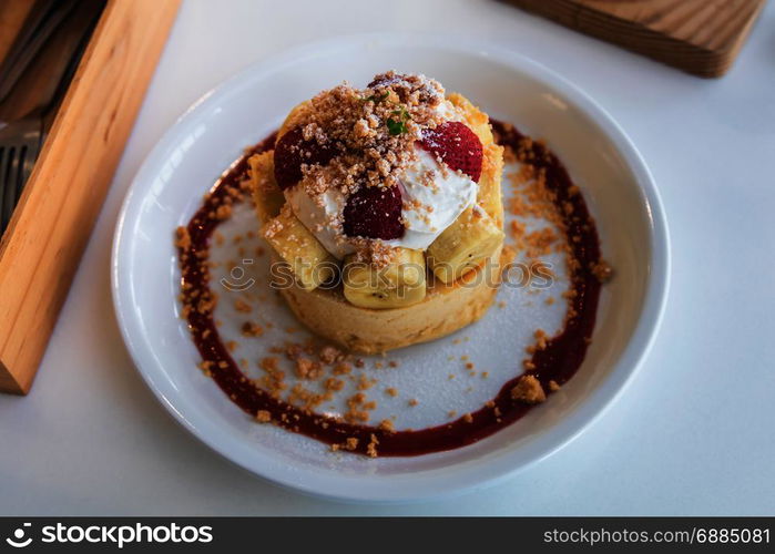 Hot cake with cream, strawberry, banana and cookie crumble on white dish