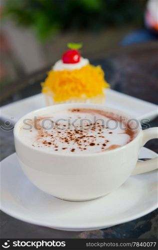 hot cappuccino in white coffee cup and sweet cake