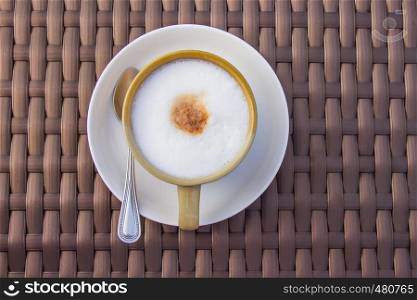 Hot capuchino coffee in a ceramic cup on bamboo wooden table. Top view