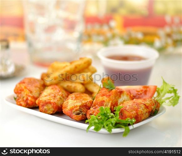 hot chicken wings with fried potatoes and sauce