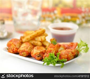 hot chicken wings with fried potatoes and sauce