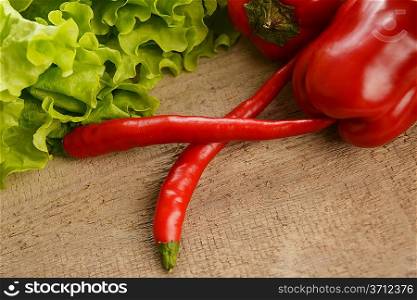 hot chili peppers and green lettuce on wooden desk