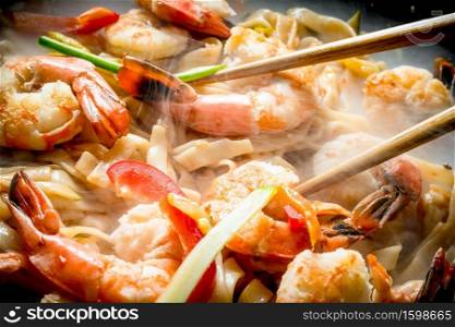 Hot Chinese wok Udon noodles with sauce, shrimp and vegetables. On rustic background. Hot Chinese wok Udon noodles with sauce, shrimp and vegetables.