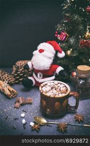 hot chocolate in a brown ceramic mug on a black background in the midst of a festive decor, vintage toning