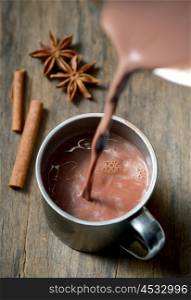 Hot chocolate with cinnamon stick on wooden table