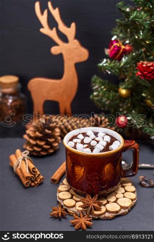hot chocolate with marshmallow slices in a brown ceramic mug on a black background and Christmas decor