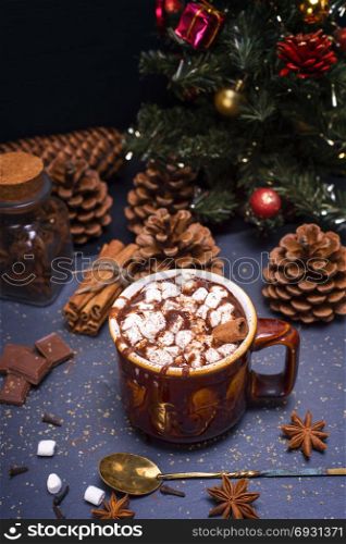 hot chocolate with marshmallow slices in a brown ceramic mug on a black background and Christmas decor