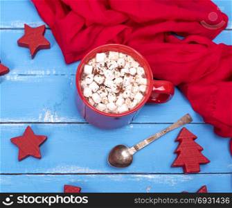 hot chocolate with marshmallows in a red ceramic mug on a blue wooden background, top view