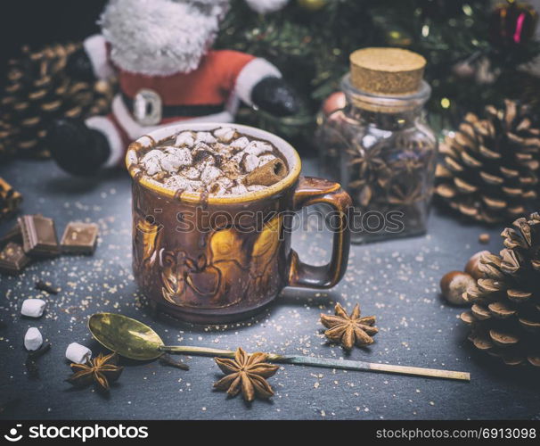 hot chocolate with white marshmallow slices in a ceramic mug on a black background near an iron spoon