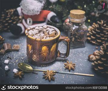 hot chocolate with white marshmallow slices in a ceramic mug on a black background near an iron spoon