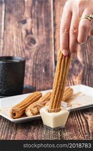 Hot churros with chocolate sauce on wooden table