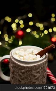 Hot cocoa drink with cinnamon stick and marshmallows with Christmas decorations on background. High quality photo. Hot cocoa drink with cinnamon stick and marshmallows with Christmas decorations on background