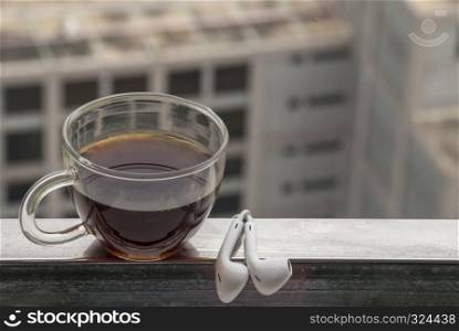 Hot coffee and headphones placed on the balcony to relax the city view.