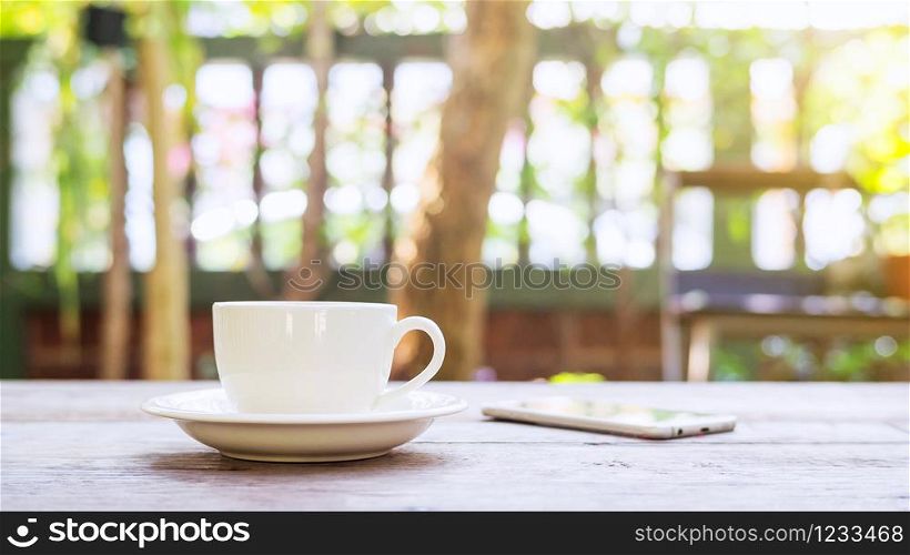 Hot coffee and smartphone on a wooden table.