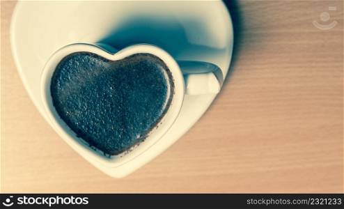 Hot coffee beverage in heart shaped cup mug on wooden board. Caffeine energy. Cross filtered.. Coffee in heart shaped cup mug. Caffeine energy.