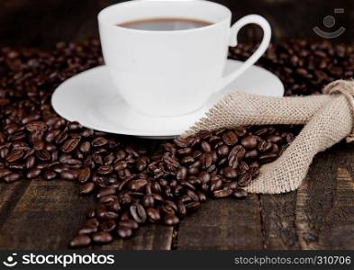 Hot coffee cup on beans for breakfast and linen on wooden board