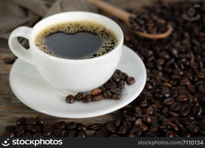 Hot Coffee cup with heart shape and Coffee beans on the wooden table.