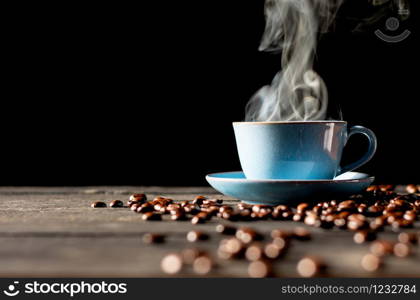 Hot coffee in blue cup and roasted coffee beans placed on a black wooden table.