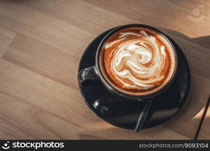 Hot coffee latte with latte art in the form of milk foam in cup mug on wood desk on top view. As breakfast In a coffee shop at the cafe,during business work concept