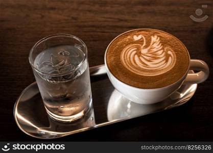 Hot coffee latte with latte art milk foam in a swan shape in cup mug on wood desk on top view. As breakfast In a coffee shop at the cafe,during business work concept