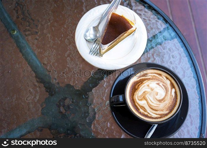 Hot coffee latte with latte art milk foam in cup mug and Homemade chocolate cake on wood desk on top view. As breakfast In a coffee shop at the cafe,during business work concept