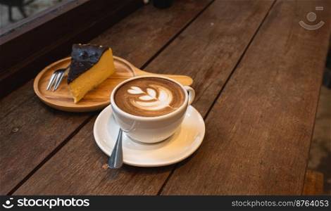 Hot coffee latte with latte art milk foam in cup mug and Homemade chocolate cake wood desk on wood desk on top view. As breakfast In a coffee shop at the cafe,during business work concept