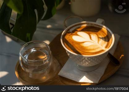 Hot coffee latte with latte art milk foam in cup mug with on marble floor background table In a coffee shop at the cafe