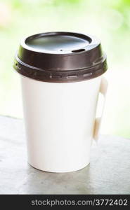 Hot coffee paper cup with green bokeh