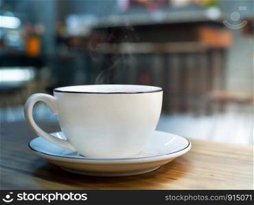 Hot coffee white cup of espresso on wood table with blur background of sunlight in cafe or coffee shop