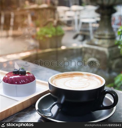 Hot coffee with latte art and cake with garden backyard in background, Lifestyle concept