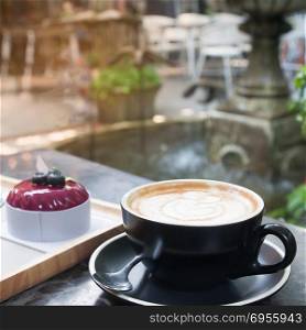 Hot coffee with latte art and cake with garden backyard in background, Lifestyle concept
