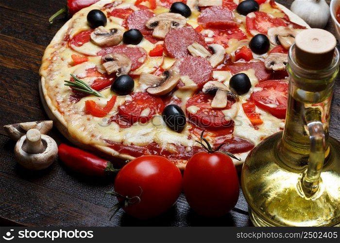 Hot cooked pizza on wooden table with mushrooms, tomato and pepper still life