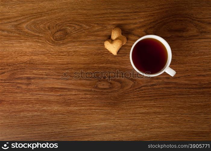 hot cup of tea with cookies on wooden table