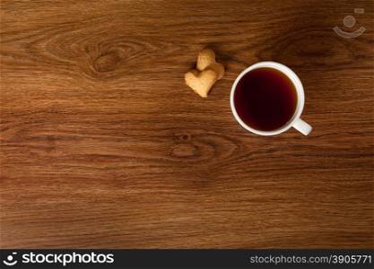hot cup of tea with cookies on wooden table