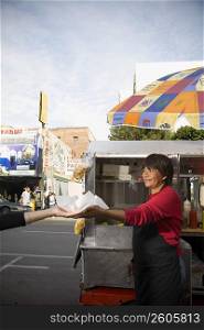 Hot dog vendor hands hot dog to customer