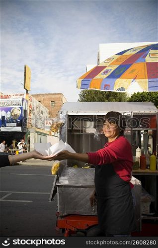 Hot dog vendor hands hot dog to customer