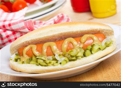 hot dog with mustard and vegetables as background