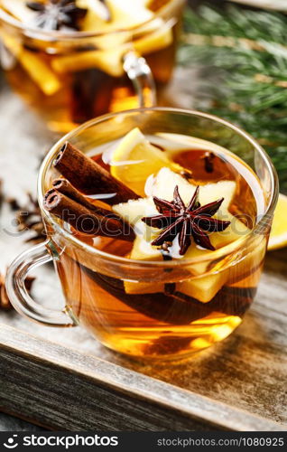 Hot drink for New Year, Christmas or autumn holidays. Mulled cider or spiced tea or mulled white wine with lemon, apples, cinnamon, anise, cloves.