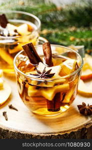 Hot drink for New Year, Christmas or autumn holidays. Mulled cider or spiced tea or mulled white wine with lemon, apples, cinnamon, anise, cloves.