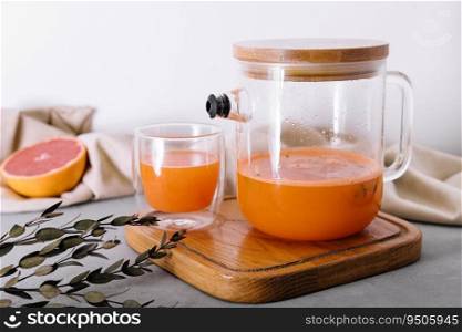 Hot drink from a sea-buckthorn in a glass cup and jug