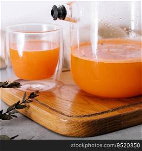 Hot drink from a sea-buckthorn in a glass cup and jug