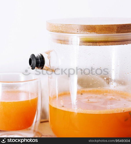 Hot drink from a sea-buckthorn in a glass cup and jug