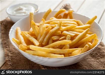 Hot golden french fries with sauce on a wooden background. Homemade rustic food.. Hot golden french fries with sauce on wooden background. Homemade rustic food.